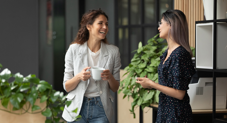 Two young coworkers having a conversation in a modern office