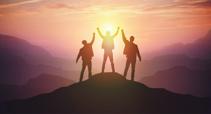 Three business professionals on the top of a mountain